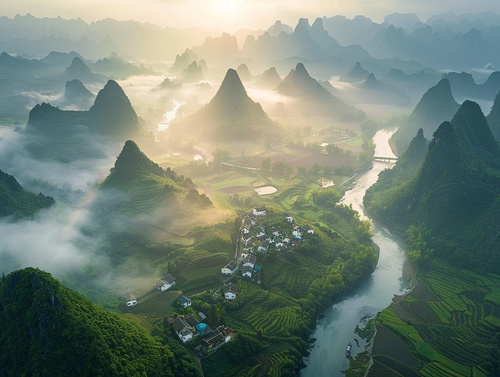 桂林山水甲天下，十万大山如画。高空航拍，青翠的山峰和山脉拔地而起，轻雾笼罩在山峰之间，宛如水墨画。小村庄位于翠谷山谷中，白墙黛瓦与山川交融，夕阳照耀，温暖的色调熏染山腰，古朴与自然和谐共存。远眺，漓江蜿蜒曲折，倒映着群山的倩影，如梦如幻，呈现出瑰丽静谧的艺术风貌。32件，超高清摄影