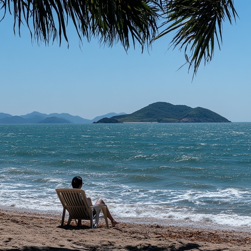 美丽的大海，海浪怕打在沙滩上，远处有一座小岛，一个人休闲坐在沙滩椅上，望着远处大海