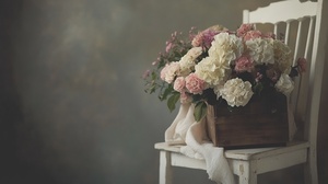 A homely scene with a focal point of a bouquet of pink and white flowers placed on a white chair. The bouquet of flowers is placed in a wooden box with a cloth tablecloth inside, adding a touch of elegance to the whole scene. The chairs are placed next to a gray wall, providing a neutral background for the entire frame. The overall color palette of the picture is warm and inviting, showing a cozy, welcoming atmosphere.ar16:9，v6