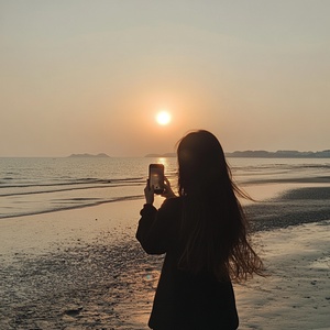 女孩在汕头海滩拍摄日落照片